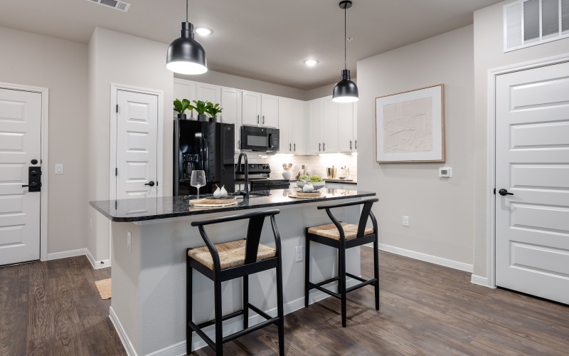 Open bright kitchen with white cabinets and black granite